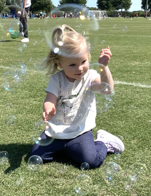 image of girl outside in grass surrounded by bubbles